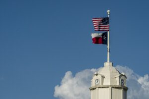 United States and Texas flags flying above a courthouse clock tower