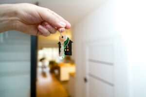 Hand holding house keys at the door of a rental home